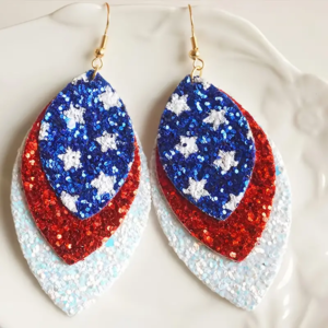 Image shows a pair of red, white and blue earrings. Each color is a layer in a teardrop shape, increasing in size by layer. The blue layer shows stars.