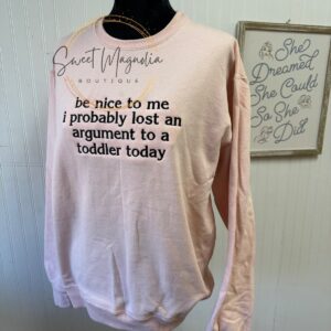 Image shows a mannequein wearing a blush colored sweatshirt , which is embroidered with black thread reading: Be nice to me. I probably lost an argument to a toddler today.