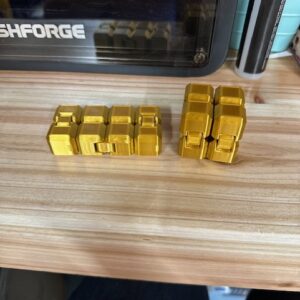 Image of two 3D Printed Cubes, side by side. The cube on the left is open, and the cube on the right is closed. The cubes are designed to be a toy that can be manipulated around to provide entertainment.